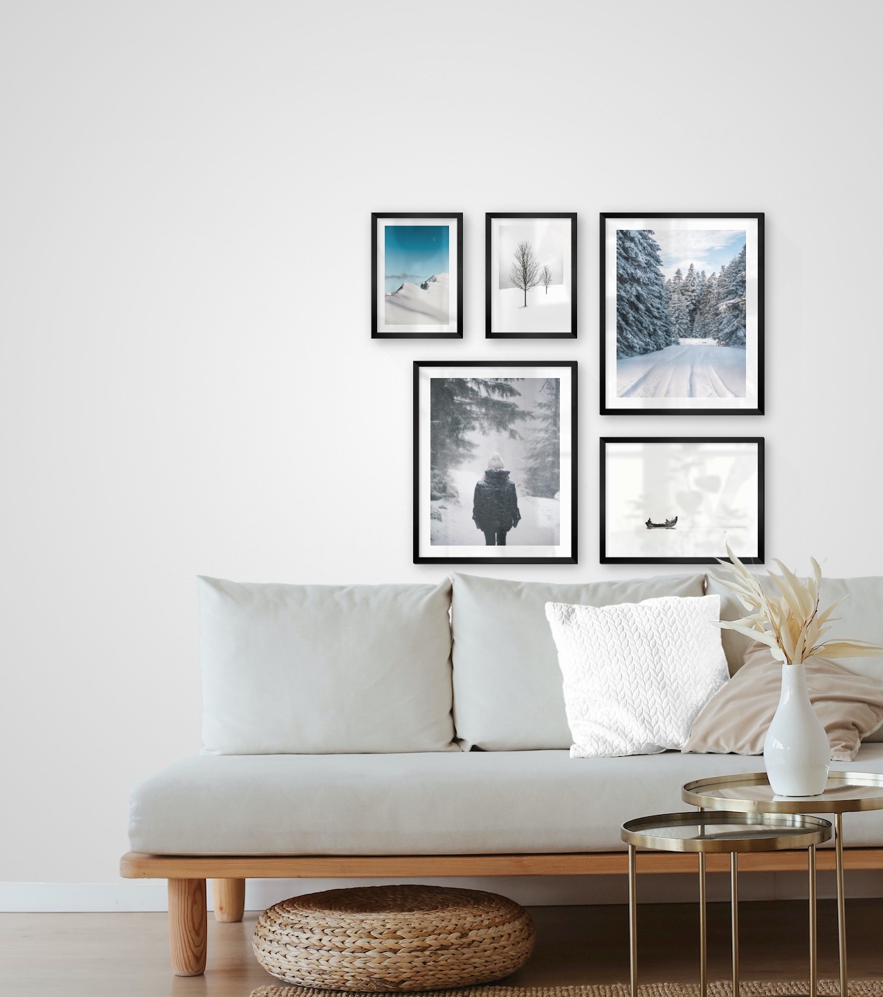 Tavelvägg med ramar i svart i storlekar 21x30, 40x50 och 30x40 med posters med "Träd i snön", "Snöiga bergstoppar", "Person i snön", "Snöig väg" och "Människor i båt"