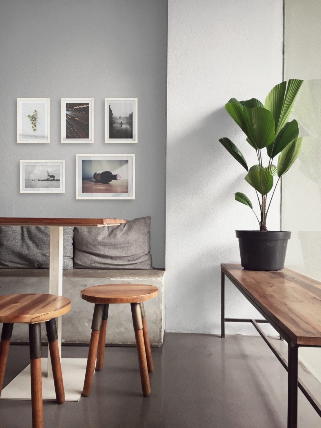 Tavelvägg med ramar i ljust trä i storlekar 21x30 och 30x40 med posters med "Örter", "Förvaring av vin", "Regnig stad", "Pir med byggnad" och "Vinflaska på bord"