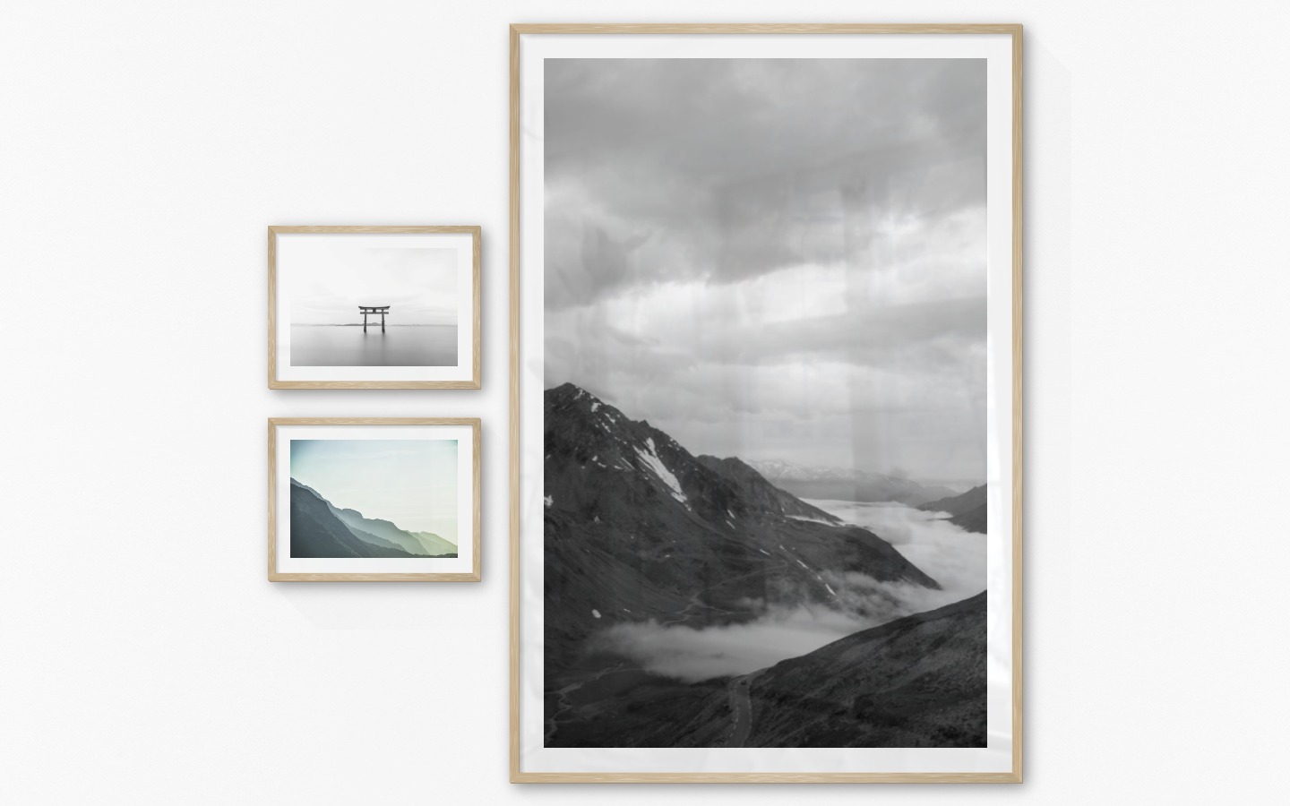 Tavelvägg med ramar i trä i storlekar 30x40 och 100x150 med posters med "Pelare i vattnet", "Dimmigt berg" och "Väg bland berg"